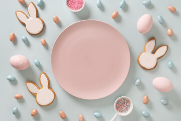 Easter homemade bunnies shaped cookies, eggs and pink plate as mock up on blue background. View...