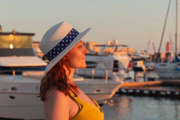 Female looking at yachts and boats moored at the seaport against the background of a colorful...