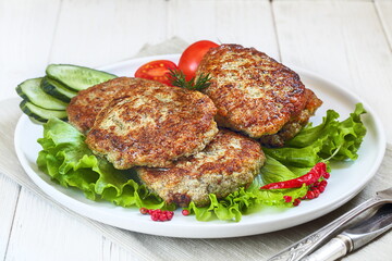 Cutlets on a plate on a white, wooden background	
