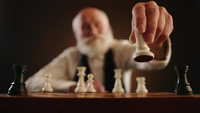 A tense moment in chess an elderly man contemplates and swiftly removes an opponent's piece, significantly altering the course of the game. Camera 8K RAW. 