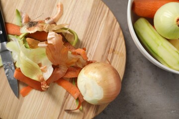 Peels of fresh vegetables and knife on grey table, flat lay