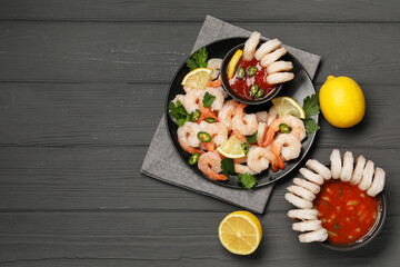 Tasty boiled shrimps with cocktail sauce, chili, parsley and lemon on grey wooden table, flat lay. Space for text