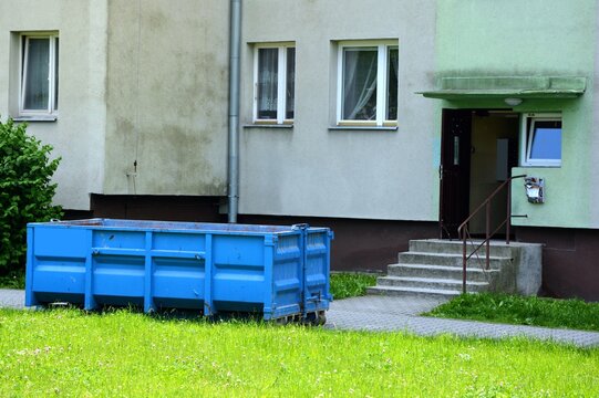 Empty rubble dumpster next to an apartment block