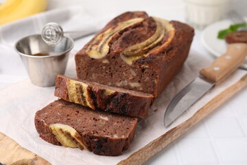 Delicious banana bread on white tiled table, closeup