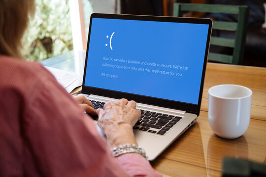 Woman with laptop showing Blue screen of death or BSOD on the monitor screen. Faulty Microsoft operating system Windows 10.