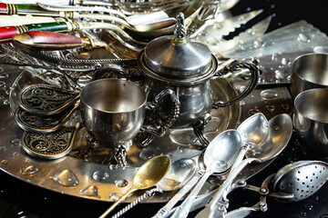 Antique silver cutlery, forks, spoons, knives, in a composition on a black background.