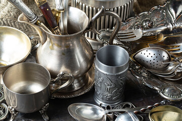 Antique silver cutlery, forks, spoons, knives, in a composition on a black background.