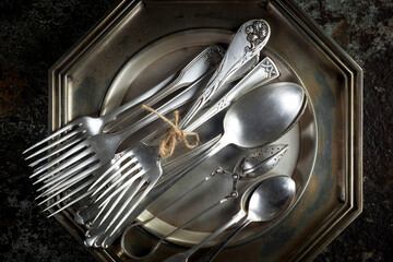 Antique silver cutlery on a dark background in a composition on a table.