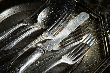 Antique silver cutlery on a dark background in a composition on a table.