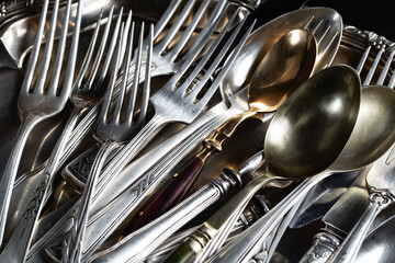 Antique silver cutlery on a dark background in a composition on a table.