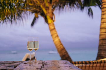 Two glasses of champagne in an outdoor cafe on an island, palm trees, sea, sunset 