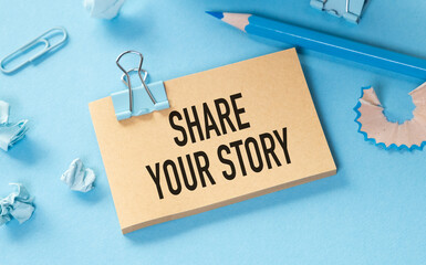 Blue and Brown Background with Share Your Story Paper Note, Pencil, and Paper Clips