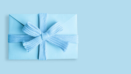 Light blue envelope with a bow on a Light blue background.