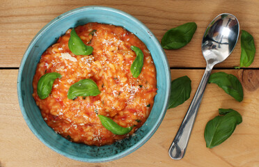 Delicious tomato risotto in bowl with basil on a wooden table