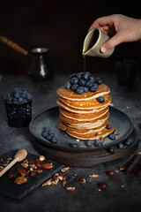 Pile of pancakes with blueberries on a plate on a dark background 