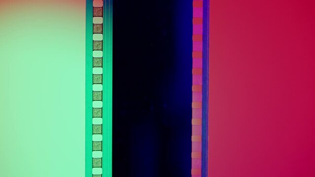 Vertical film strip on a pink and white gradient background, close up. 35mm film slide frame. Long, retro film strip frame. Copy space.