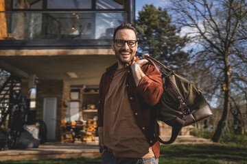 Fototapeta na wymiar Portrait of one man happy caucasian male with travel bag at his house
