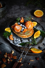 Pile of pancakes with oranges on a plate on dark background 