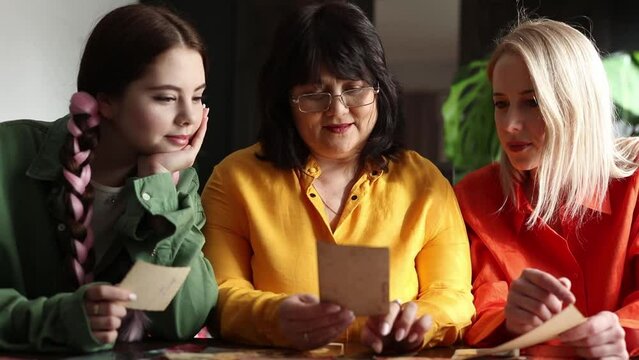 mother and daughters looking at old family photos at home