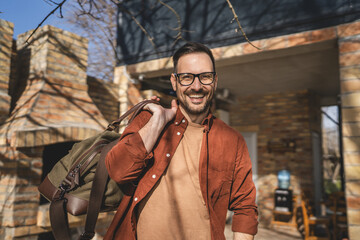 Portrait of one man happy caucasian male with travel bag at his house