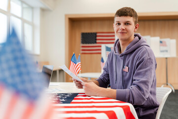Young smiling  man, voter holding paper ballot waiting registration at polling station. Election...
