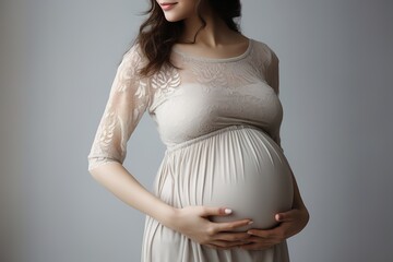 Pregnant young woman in a light dress gently holds her belly