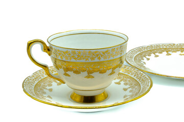 Antique bone china cup saucer and tea plate in gold painted flower design and gold gilt edging on a white background