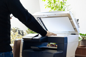 A man is using a copier. A man scans or copies documents on a copy machine. Working with a scanner in the office