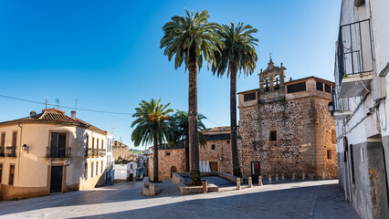 Palm-fringed square and old church in the monumental town of Caceres, Spain.