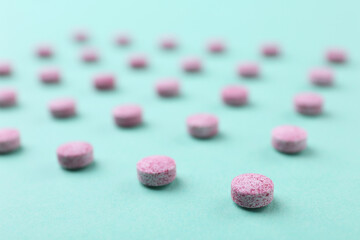 Obraz na płótnie Canvas Many pink vitamin pills on turquoise background, closeup