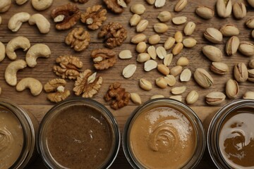 Nut butters in bowls and ingredients on wooden table, flat lay