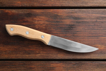 One sharp knife on wooden table, top view