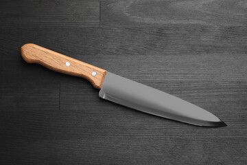 One sharp knife on black wooden table, top view