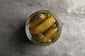 Tasty pickled cucumbers in glass jar on grey table, top view