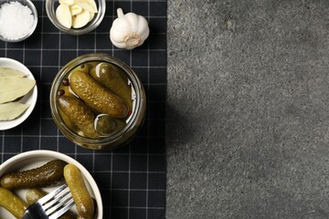 Tasty pickled cucumbers and spices on grey textured table, top view. Space for text