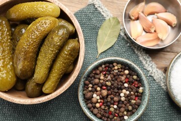 Tasty pickled cucumbers in bowl and spices on table, flat lay
