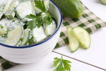Delicious cucumber salad in bowl on white table, closeup. Space for text