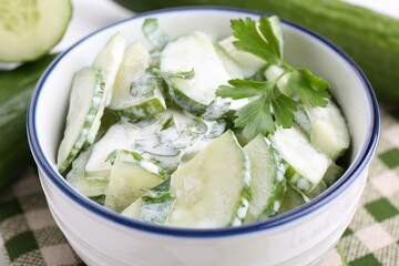 Delicious cucumber salad in bowl on table, closeup