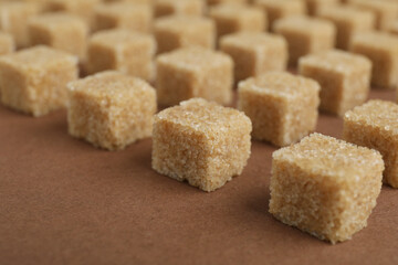 Brown sugar cubes on color background, closeup