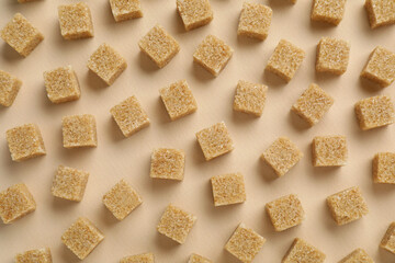 Brown sugar cubes on beige background, top view