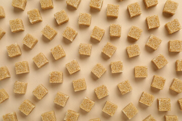 Brown sugar cubes on beige background, top view