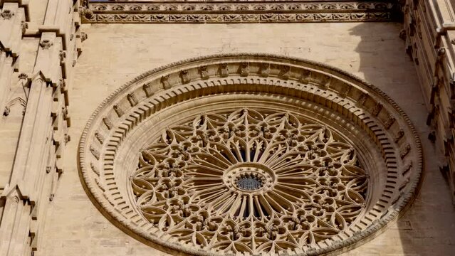 a tilt up clip of an ornate window at the front of the cathedral of santa maria of palma at mallorca in spain