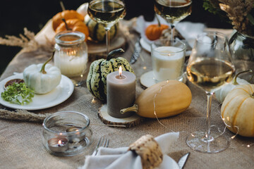 Fall still-life. Orange pumpkins, dry flowers and candles on linen tablecloth. Dinner table outdoors in the garden. Cozy autumn concept., simple handmade decoration, countryside style