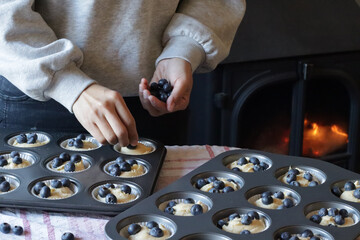Blueberry muffin cup cake homemade. Woman hand put fresh blueberry on top of cake. Family lifestyle...