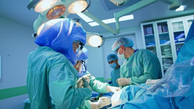 Group of surgeons begin the operation on trauma. Chief surgeon drawing mark on the patient's leg.