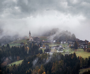 Mystic cloudy and foggy autumn alpine mountain village slopes scene. Austrian Lienzer Dolomiten Alps.