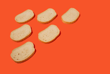 Arranged slices of fresh white bread with sesame seeds against orange background. Bakery concept. Copy space