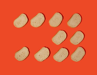 Overhead view of arranged slices of fresh white bread with sesame seeds against orange background. Bakery concept