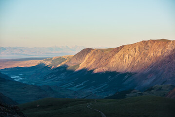 Scenic aerial top view to gold sheer crags on mountain ridge, illuminated by setting sun under clear sky in golden sunset tones. Evening alpine landscape in sunset color. Light and shadow in mountains