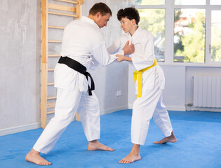 Individual judo lesson for teenager - guy and trainer are sparring in the gym